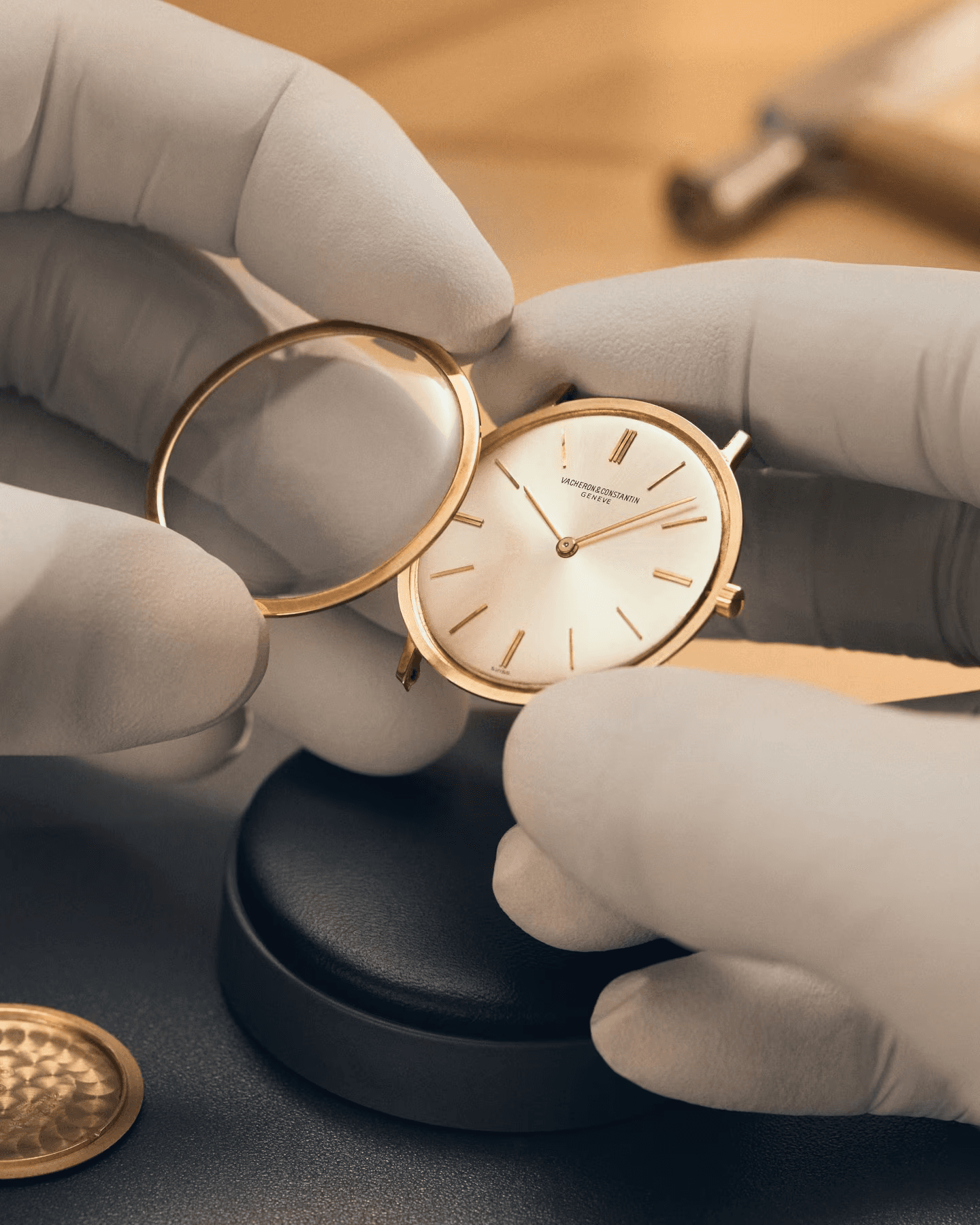 Watchmaker in gloves fitting a gold dress watch case